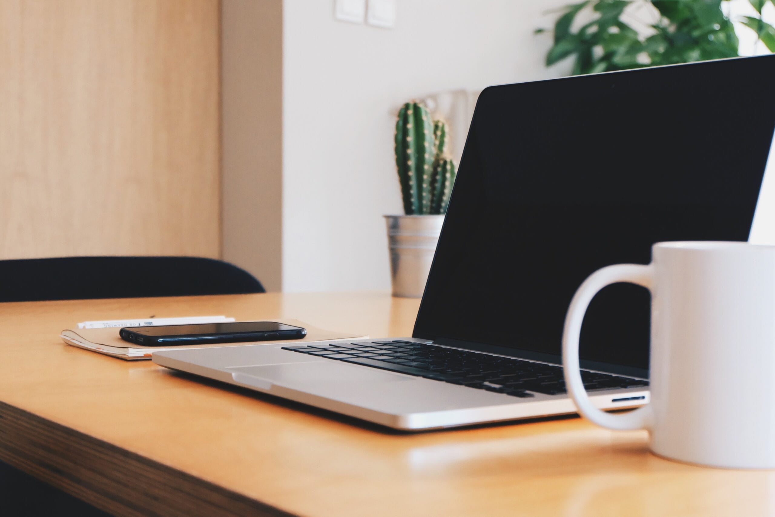 A laptop on the desk in a room, showcasing a simple home office used for virtual admin services.